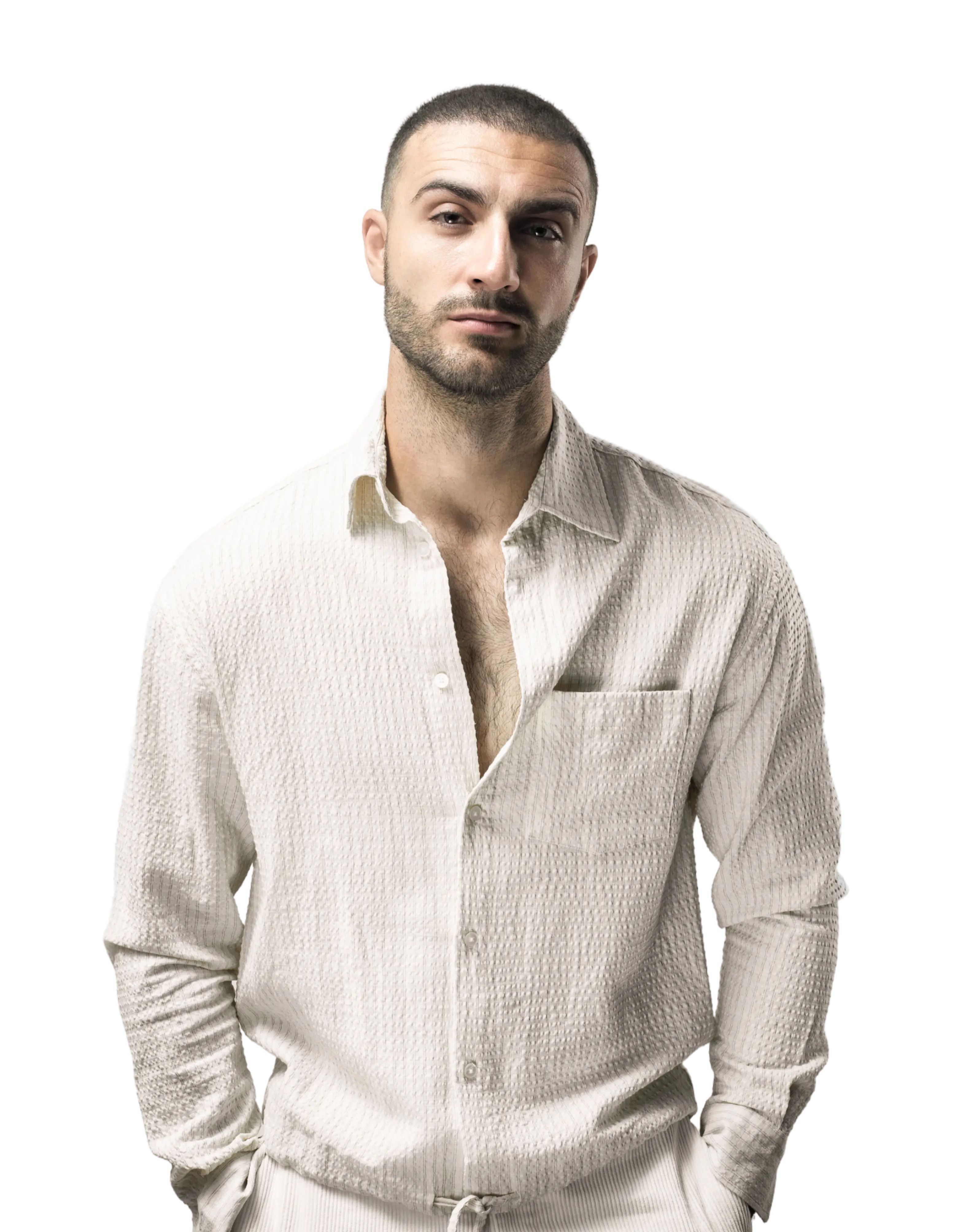 Lee Cole standing with a cream shirt on and hands in his pockets.